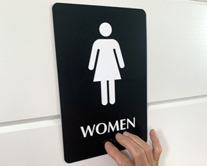 Womens restroom sign with braille